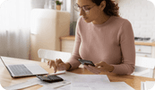 A female therapist uses her calculator while sitting at her laptop wondering about navigating private pay vs insurance clients