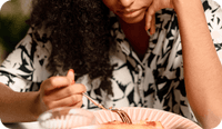 A woman holding a fork above her plate of food contemplates how to identify eating disorders