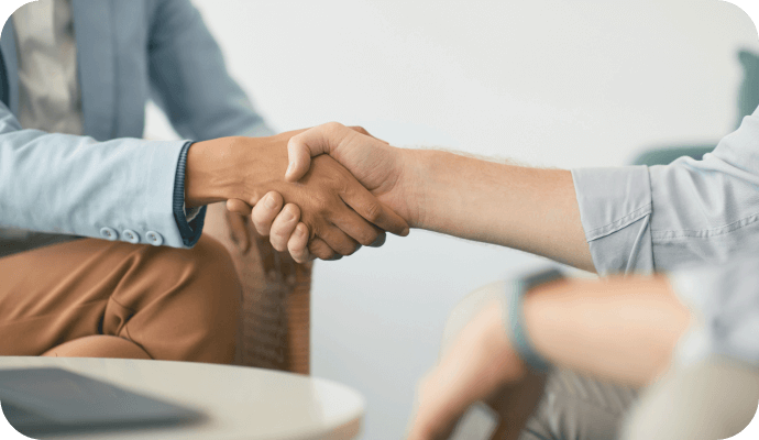 A therapist's hand reaches out to shake the hand of a client as they are about to navigate the client intake process while avoiding the mistakes that impact client retention