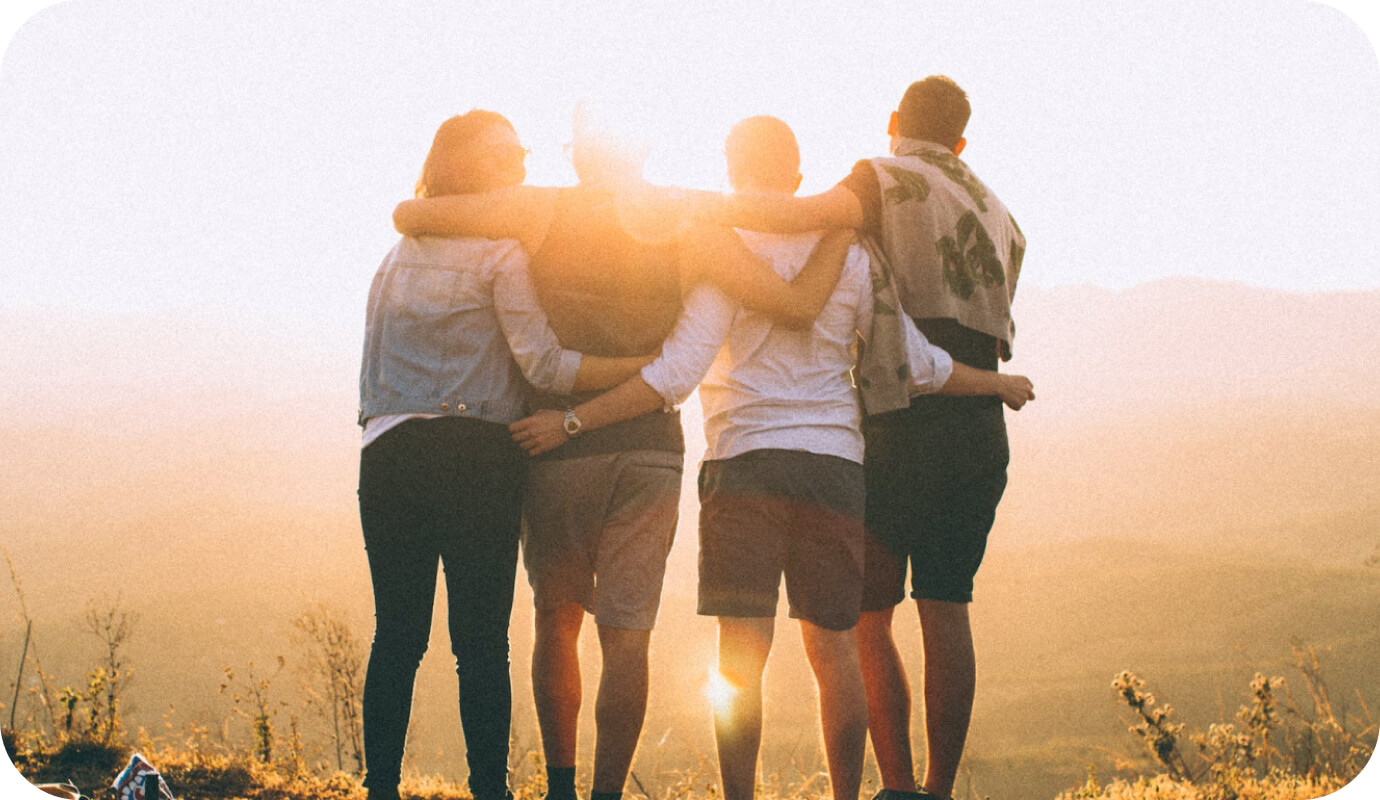 Four adults in group therapy embrace as they watch the sunset together as part of a group therapy activity