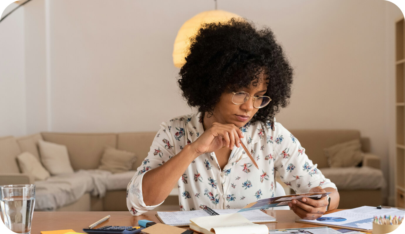 A therapist sits down at her desk with paper and pen, while holding a video call on her phone with a psychology malpractice insurance company. She is vetting various psychologist liability insurances to find out what is necessary to protect herself and her practice.