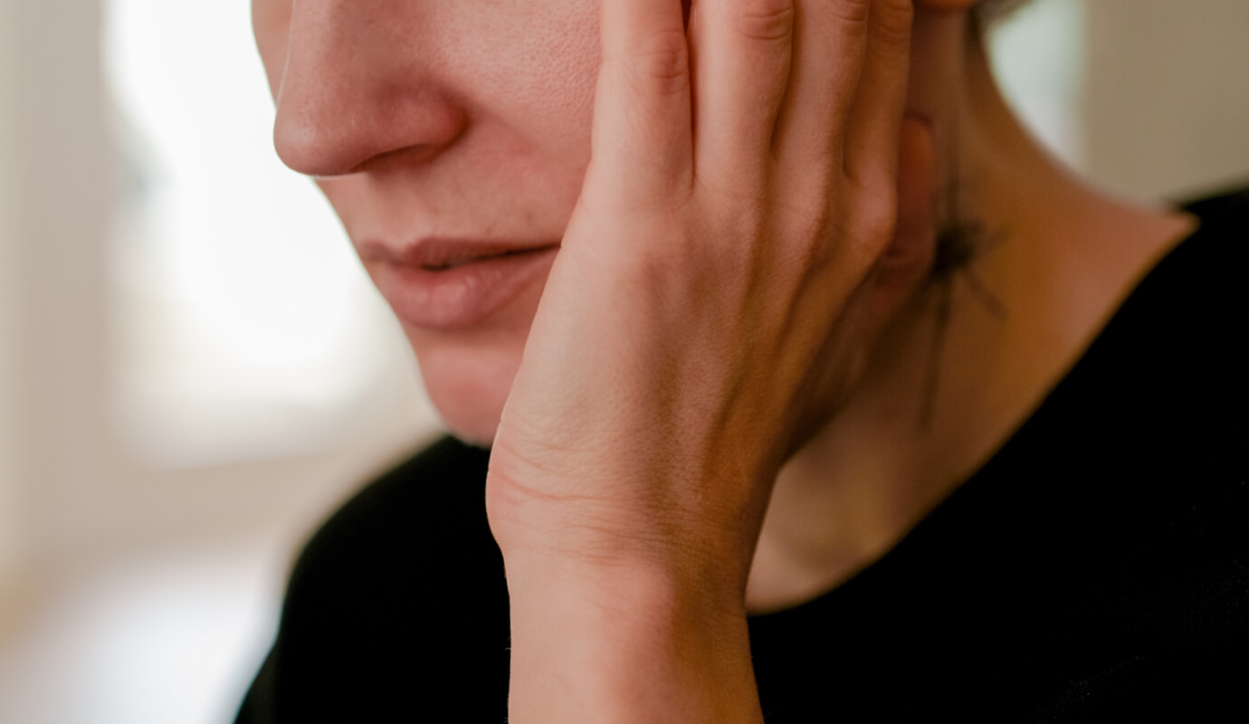 A client struggling with loneliness puts their hand up to their face in distress.