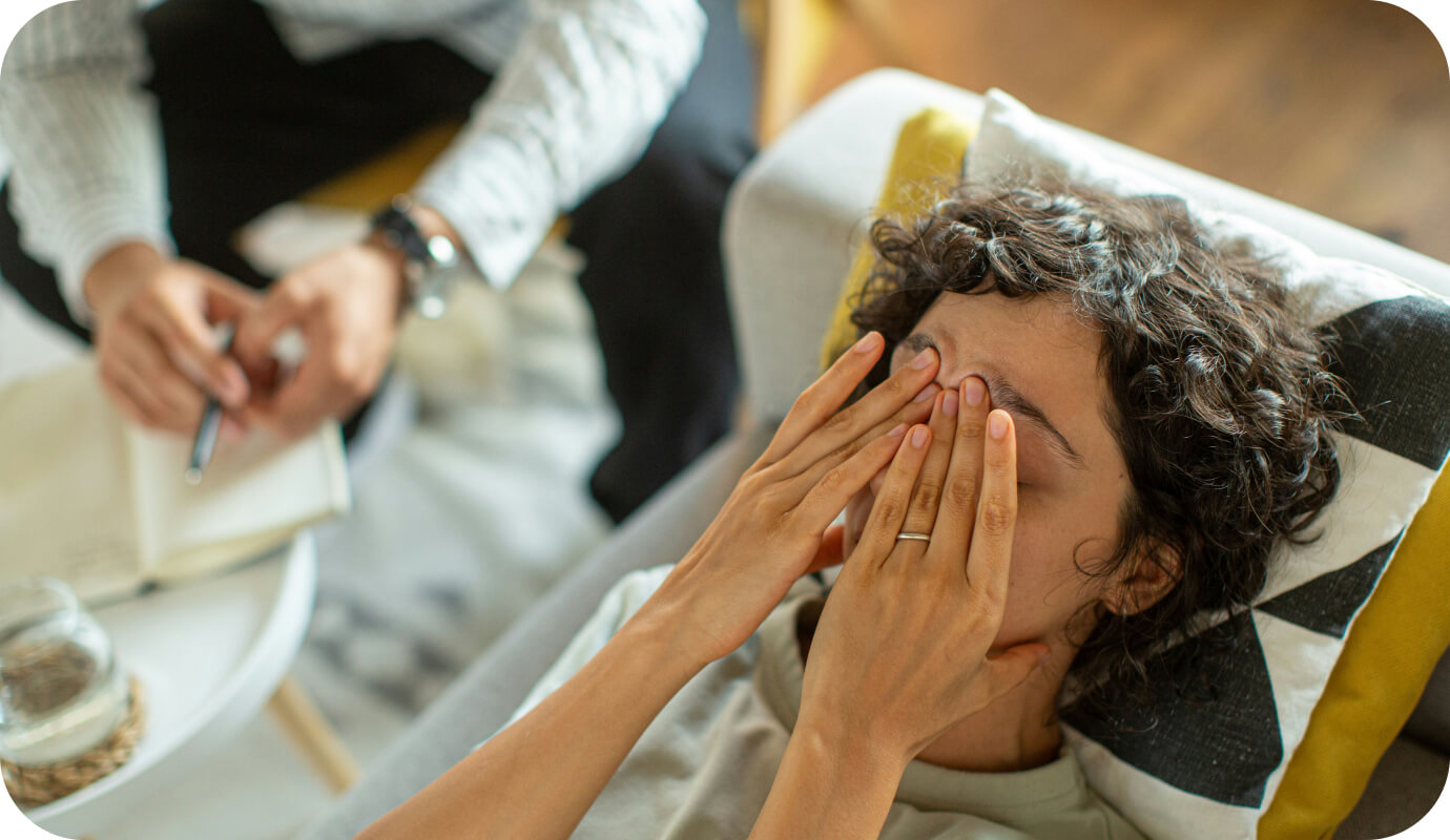 A teen client lies down on their therapist's couch and puts their hands over their eyes, a gesture that indicates resistance in therapy.