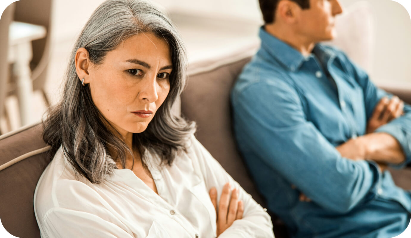 A couple seeks couples counseling. Both partners have their arms crossed on the couch.