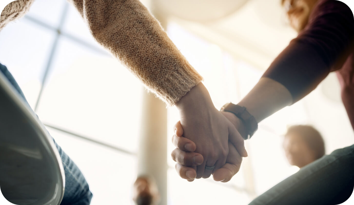 Members of a therapy support group hold hands as they participate in motivational group therapy activities