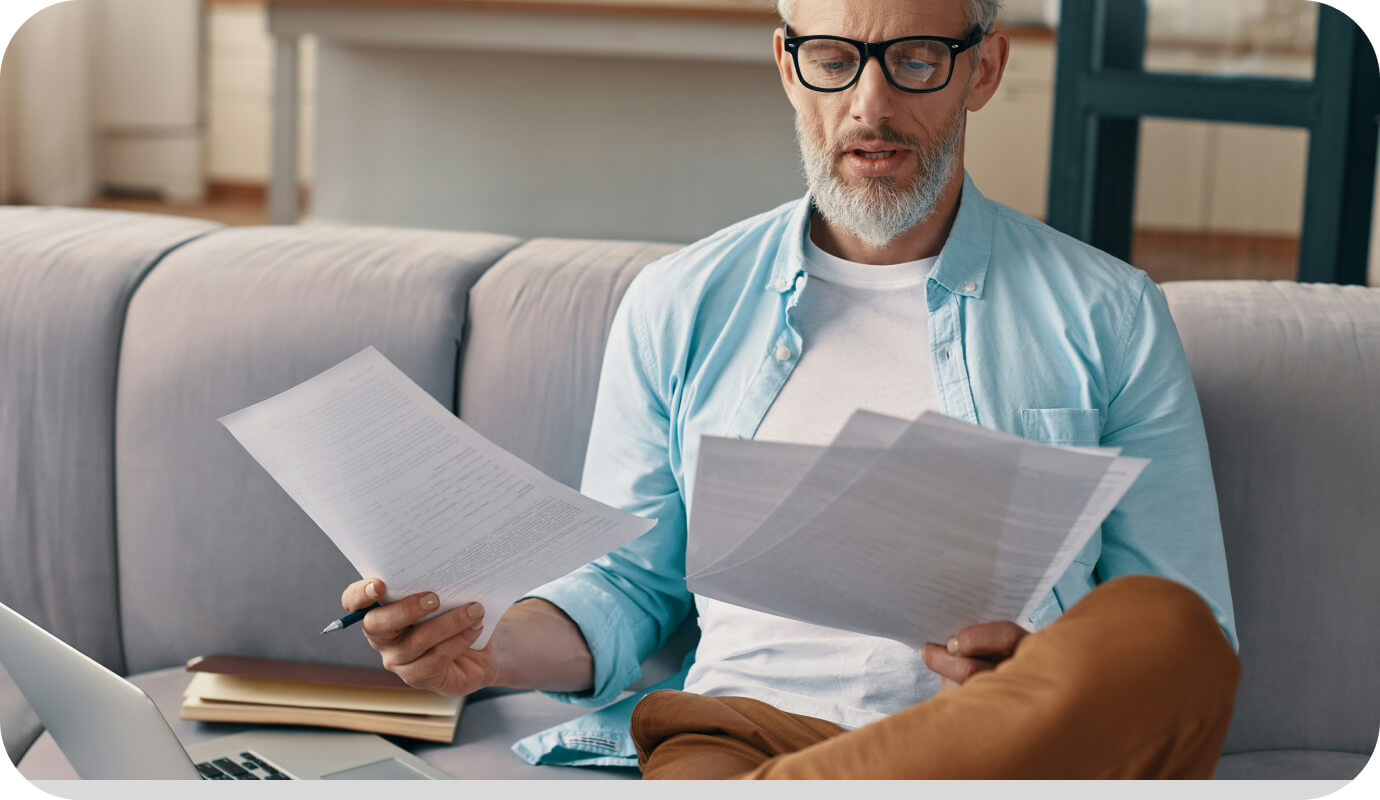 A therapist rifles through a stack of papers explaining various counselor liability insurance plans, as he looks for the right one for his practice.